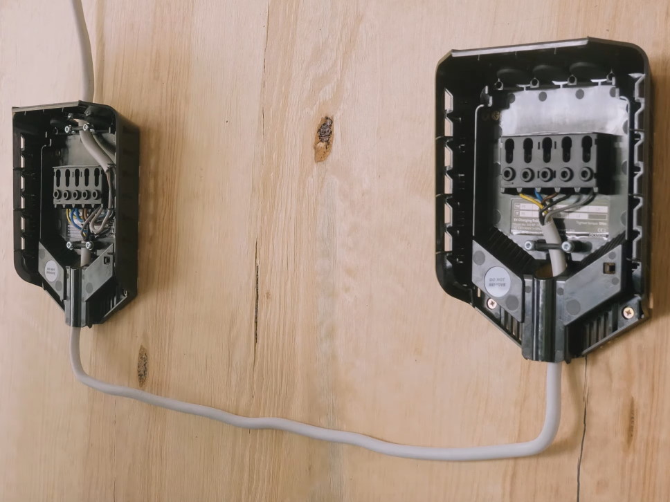 Zwei Backplates von Easee Home Wallboxen sind über ein Stromkabel miteinander verbunden